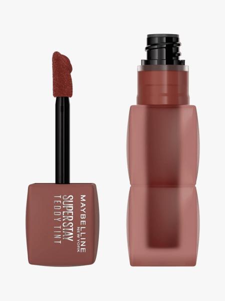 Super Stay Teddy Tint in branded dark red component next to doe foot applicator cap on light gray background